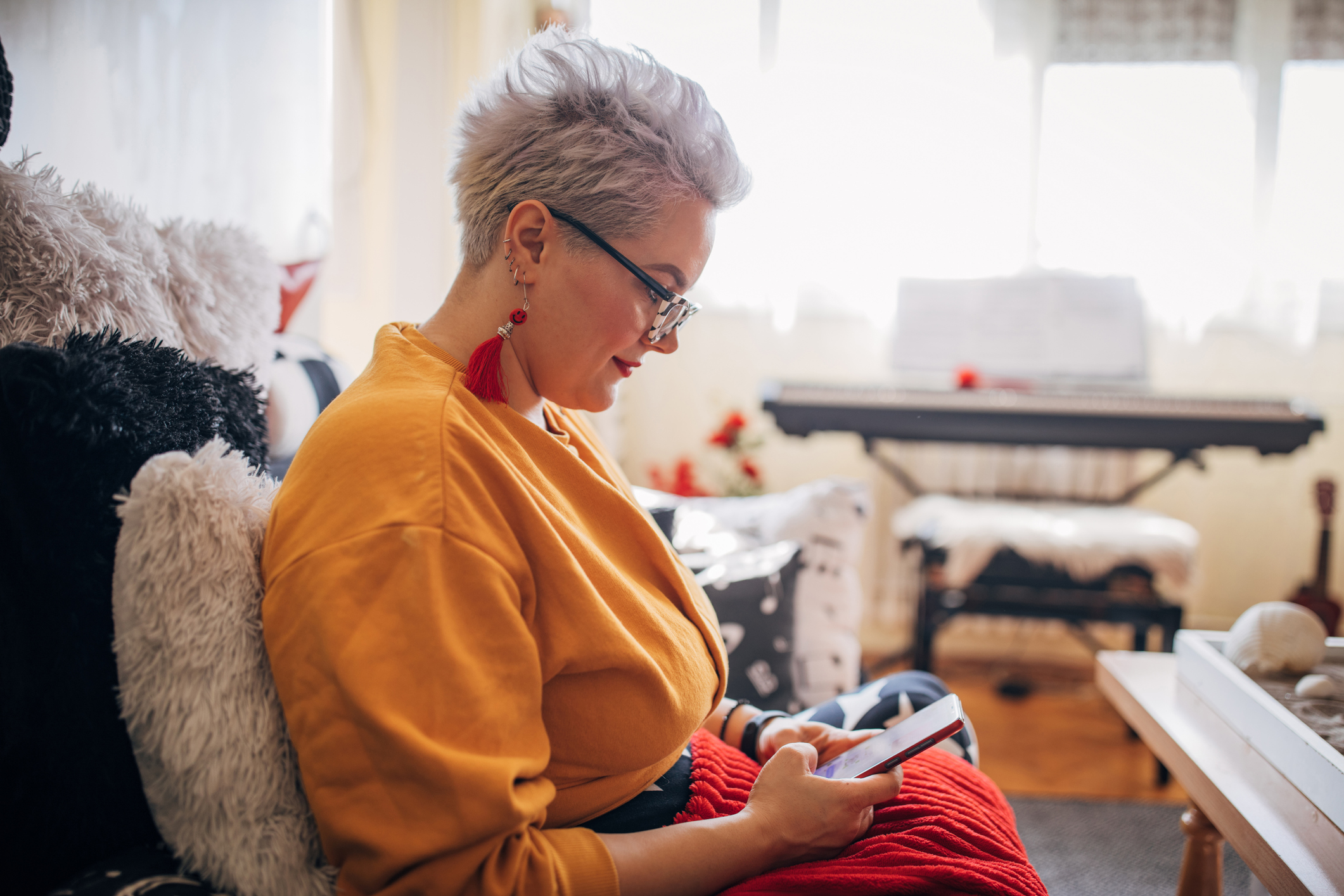 Woman sitting on sofa and using smart phone at home