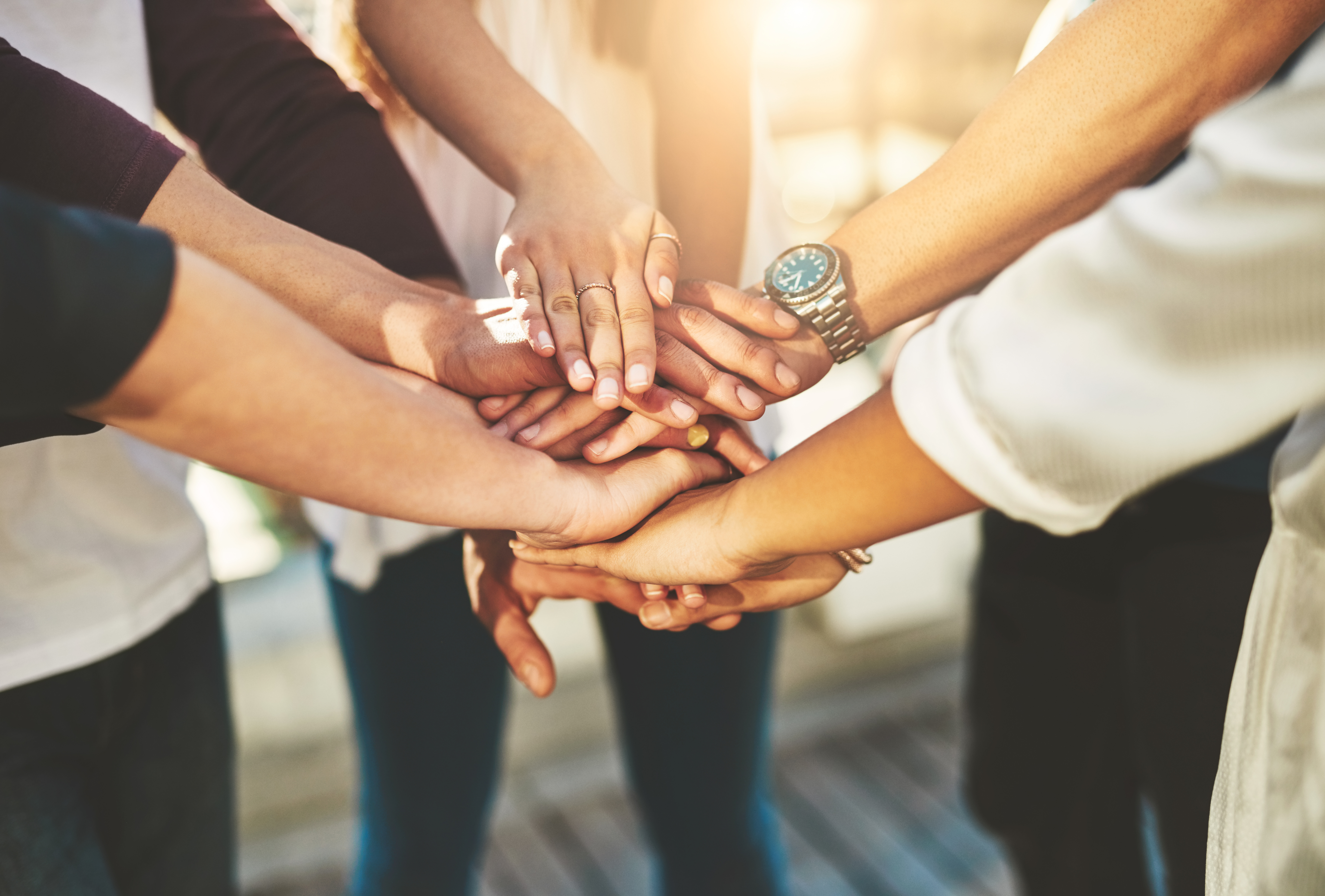 Photo rognée d’un groupe de personnes non reconnaissables joignant leurs mains en signe d’ unité à l’extérieur